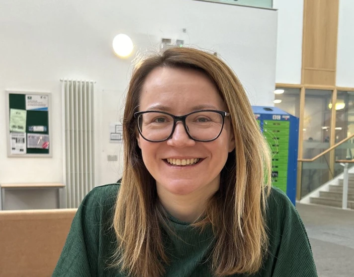 Smiling woman in a green top sitting at a table in a bright, modern college space with a “Nowhere Like Kelvin” banner in the background. Smiling woman in a green top sitting at a table in a bright, modern college space with a “Nowhere Like Kelvin” banner in the background.